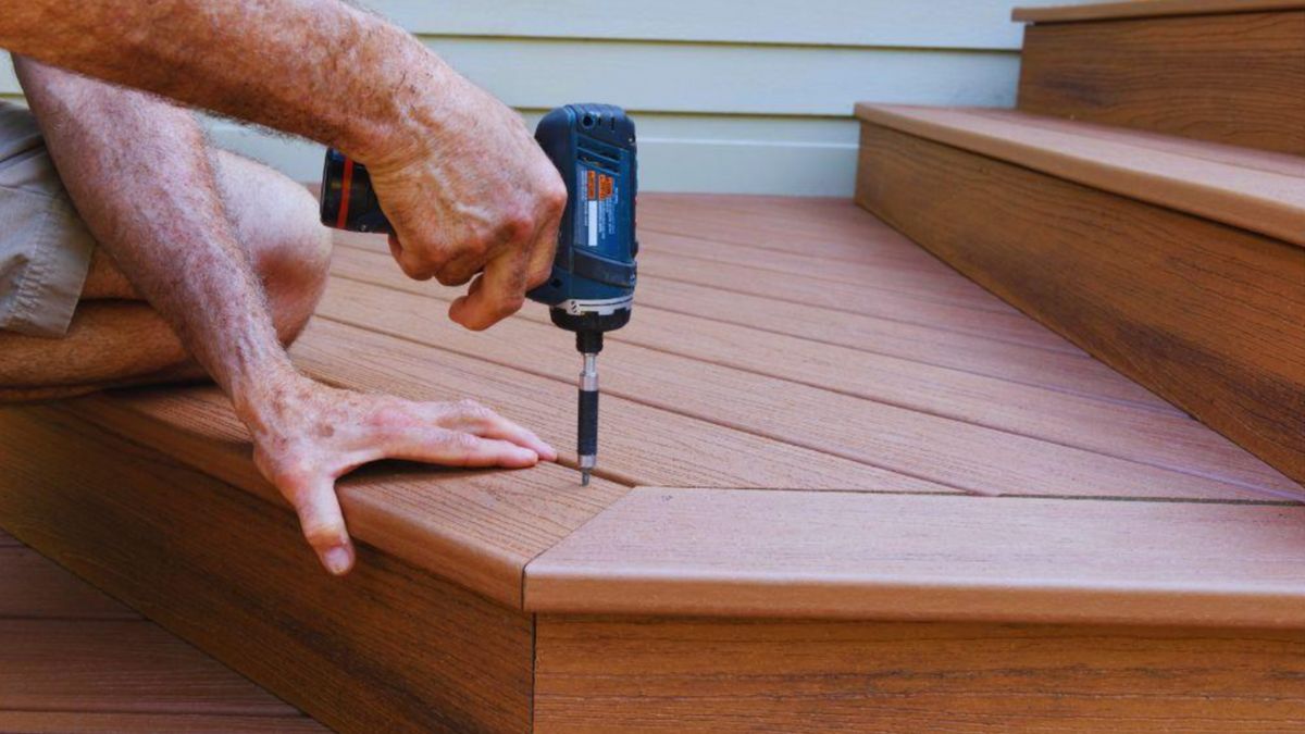 A decking contractor skillfully uses a drill to install a wooden deck in a residential outdoor space.