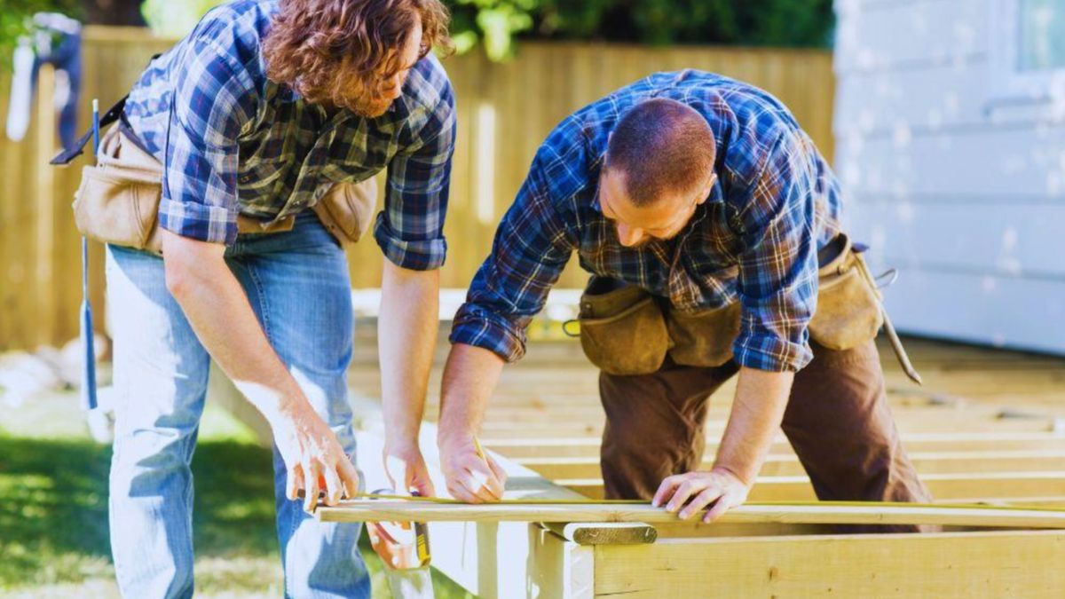 Two skilled decking contractors work together to build a beautiful wooden deck.